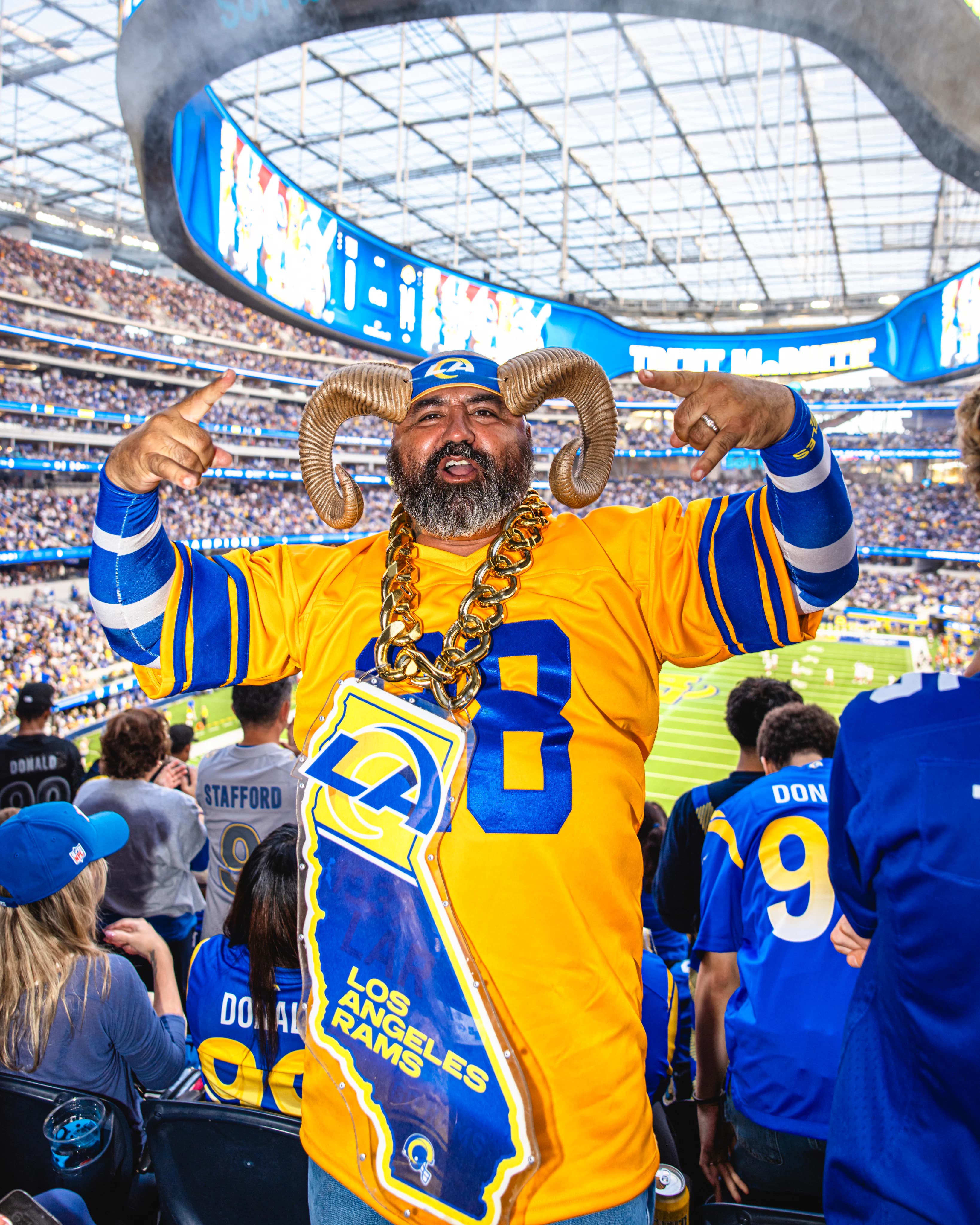 Rams fan in horns and a gold chain celebrating in the stands