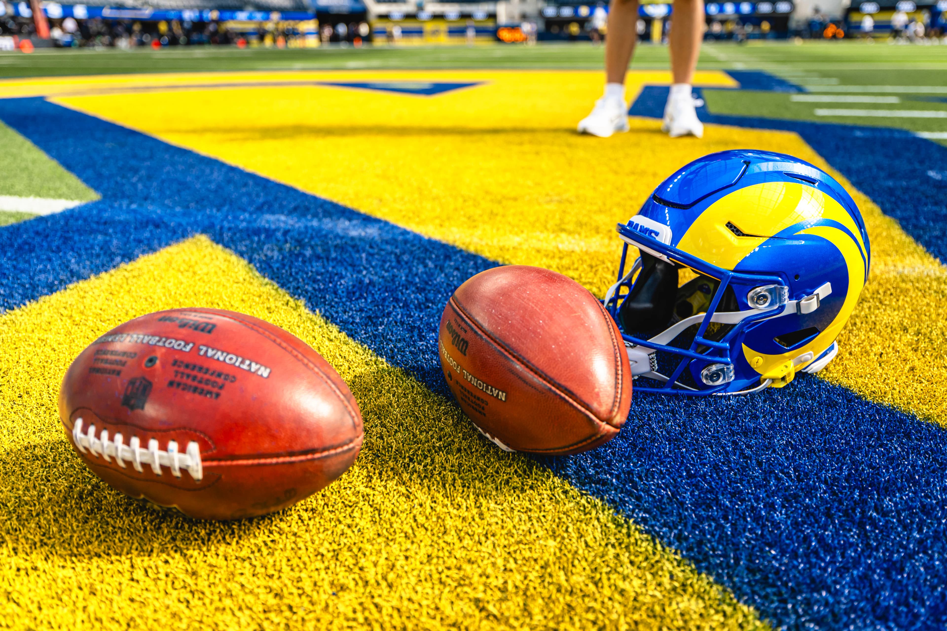 Rams helmet and footballs on the royal and sol end zone