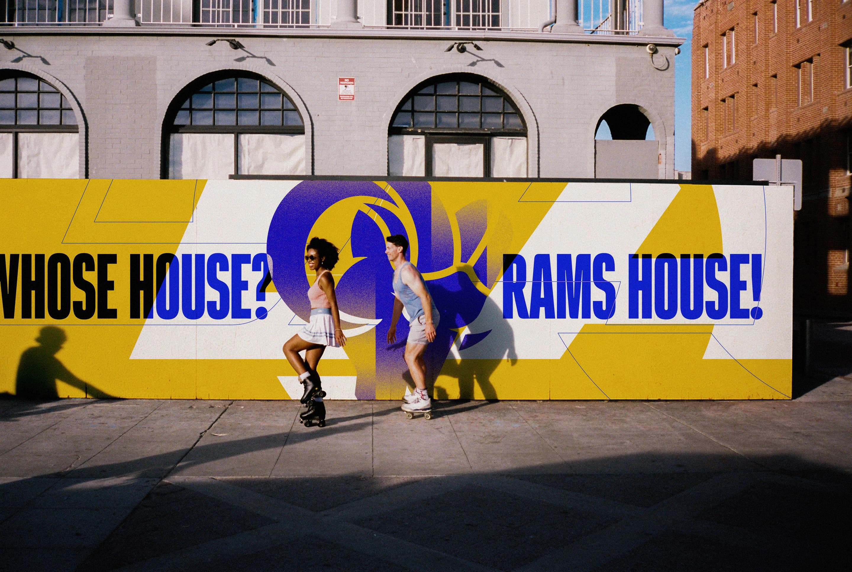 Skaters passing the Whose House? Rams House! hoarding