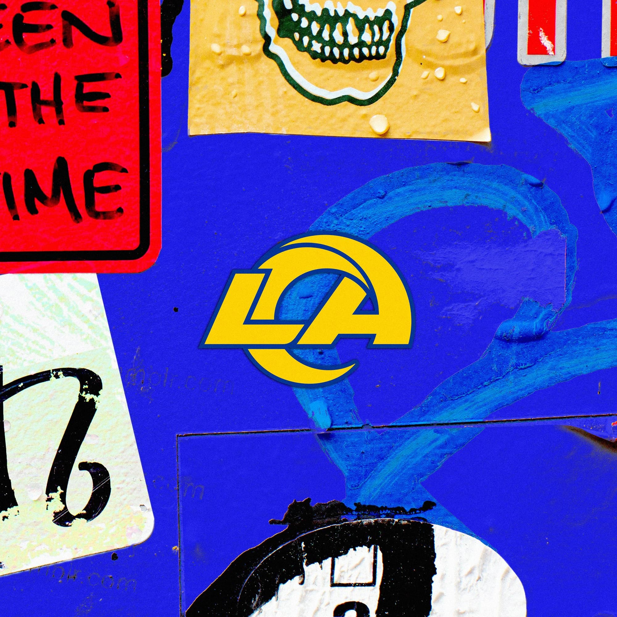 Rams stickers and blue paint on a street wall around the LA logo