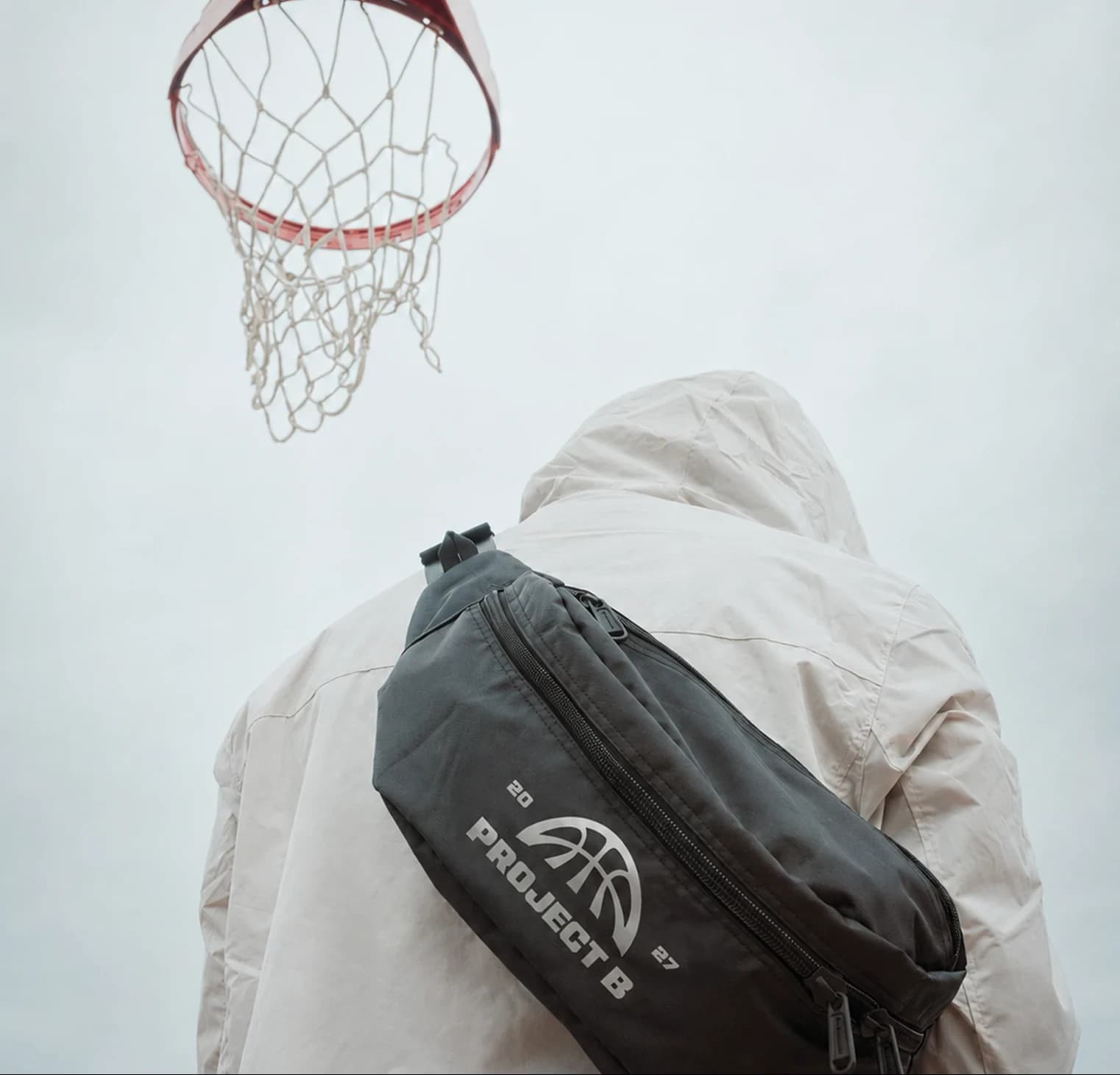 Hooded figure under a hoop wearing a Project B cross-body bag