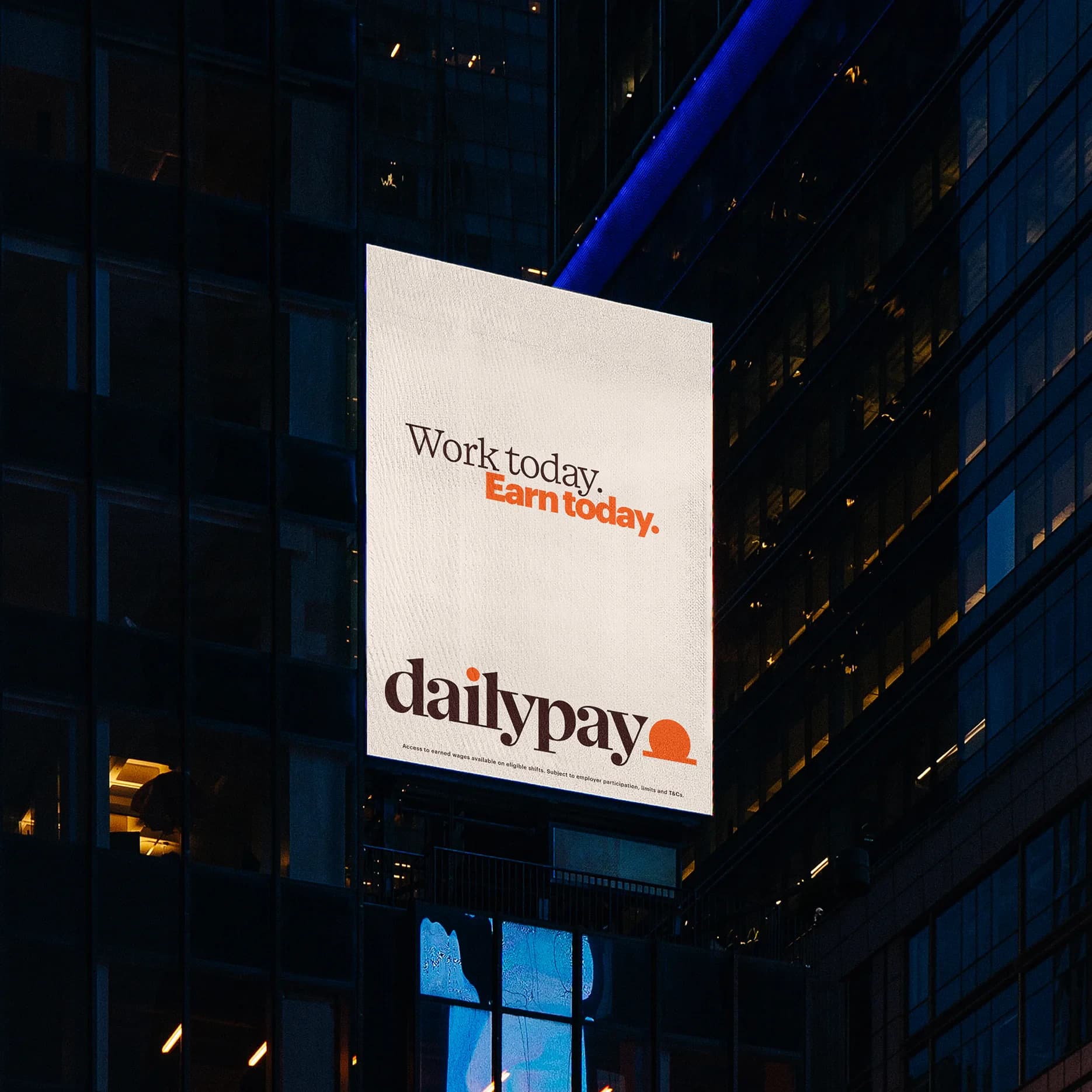 A DailyPay Work today, Earn today billboard lit on the side of a building at night