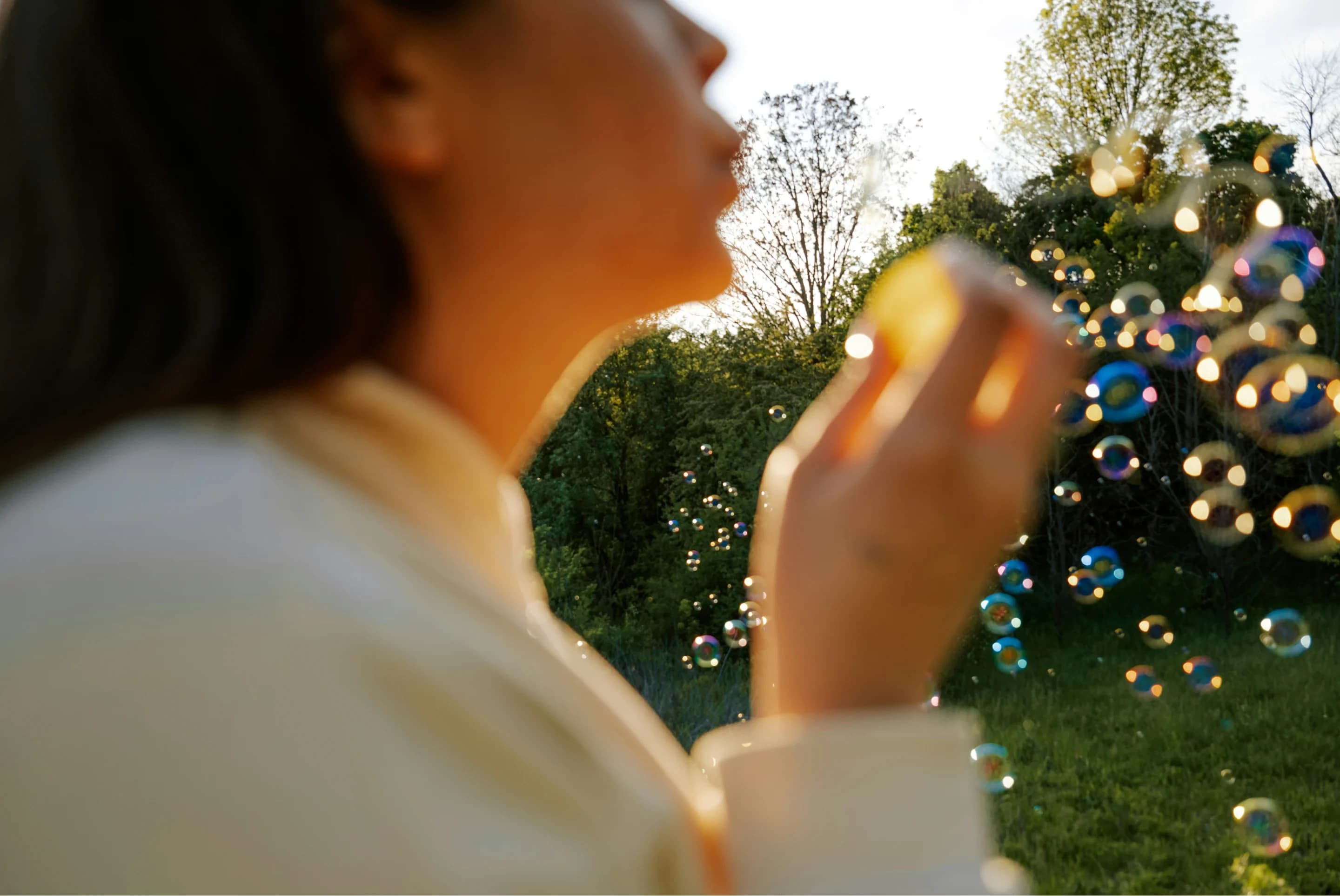 A woman blowing bubbles in a garden at golden hour