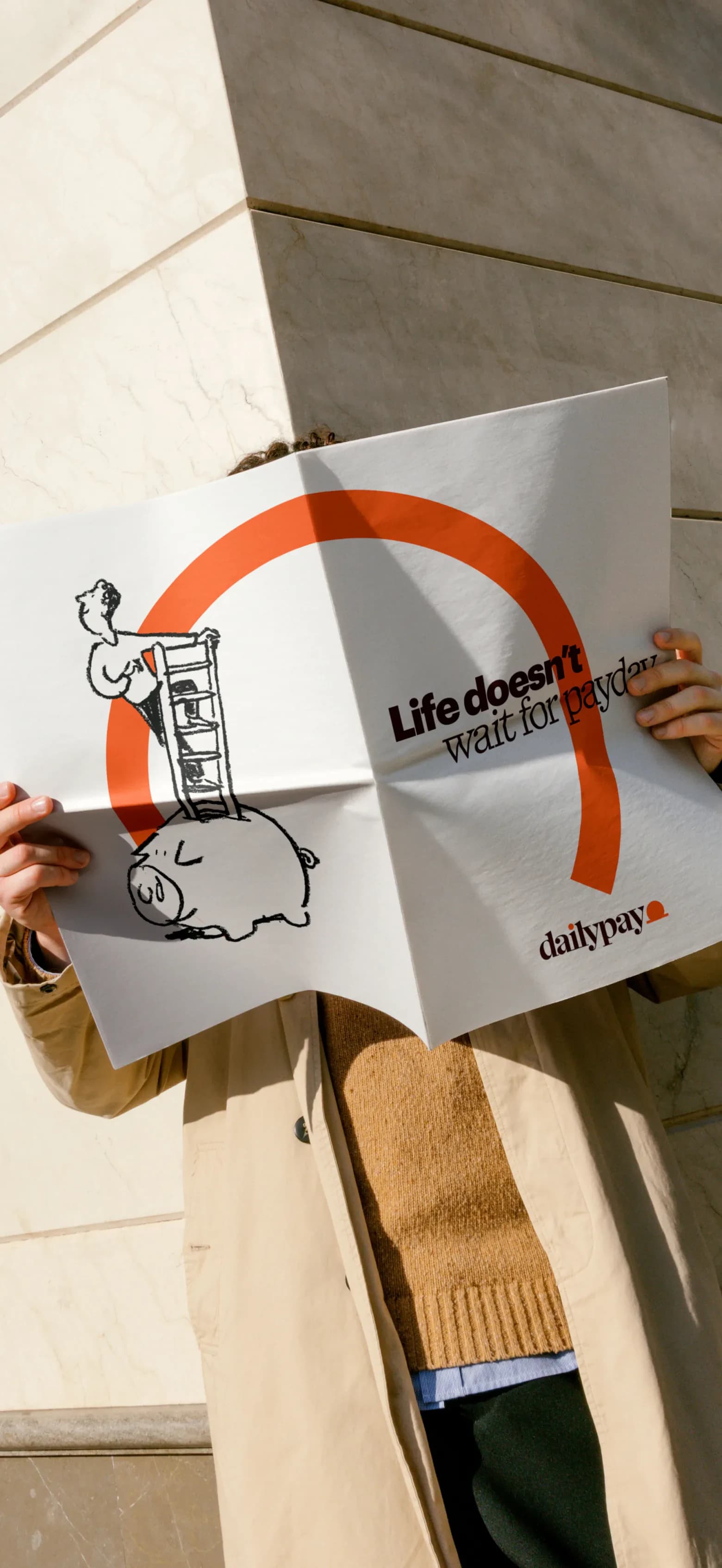 Hands holding an open DailyPay newspaper against a stone wall